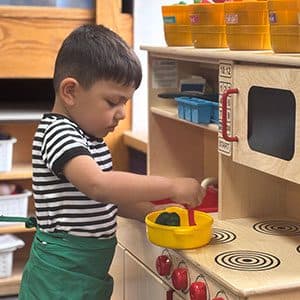 A preschooler exploring the play kitchen in a Kid's Country classroom