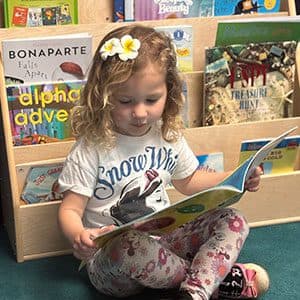 A preschooler reading a picture book at Kid's Country