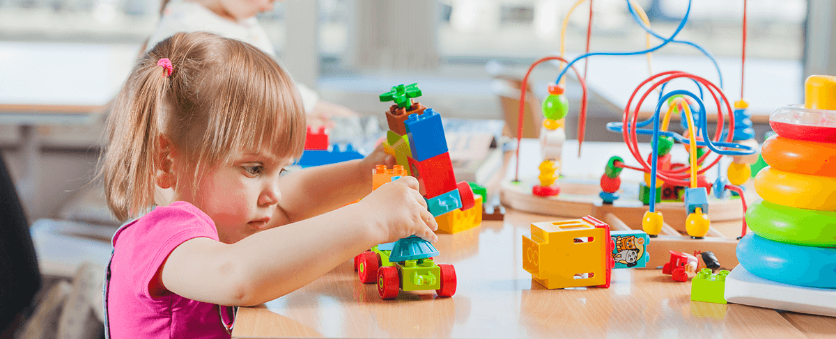A toddler building with colorful blocks at a Kid's Country table